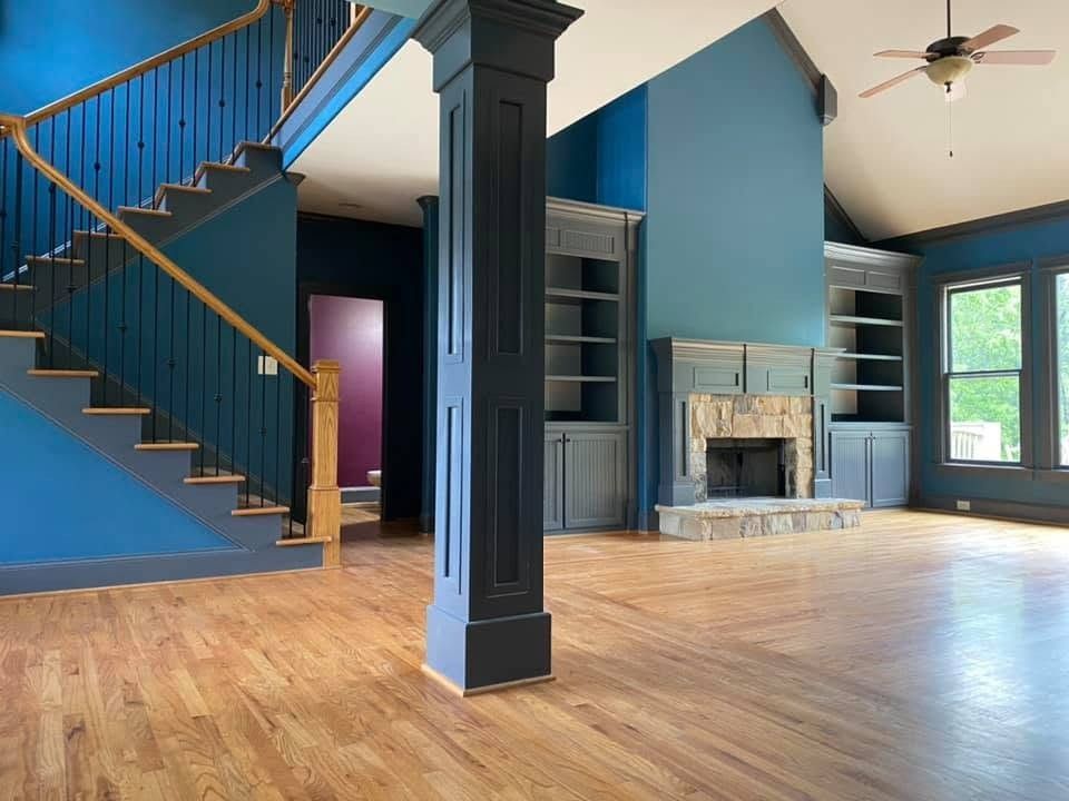 Two-story great room painted deep teal and blue with dark built-ins and column