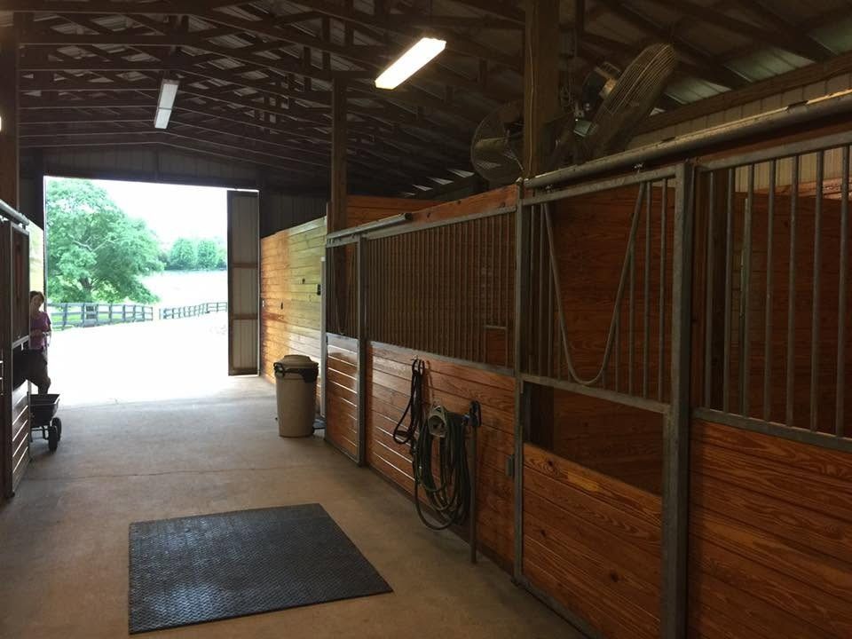Inside a horse barn with wood stall fronts